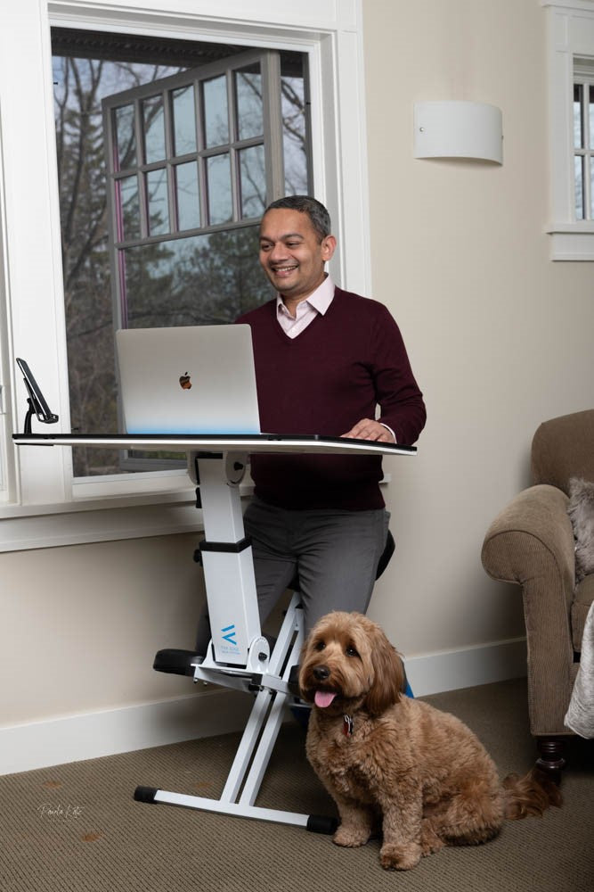 Man happily using the edge desk ergonomic kneeling desk as an adjustable workstation with his dog at home